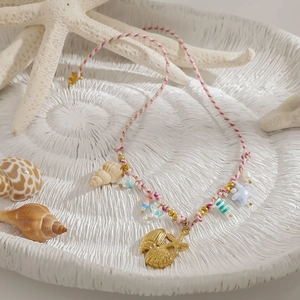 Details von rosa geflochtener Halskette mit goldenen Seesternen und Perlen