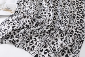 Close-up of leopard print satin scarf showing smooth silk-like texture and monochrome pattern