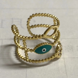 Detailed macro view of a gold-plated multi-layer ring with blue evil eye and crystals