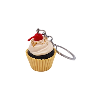 Realistic mini cupcake keychain with pink frosting and red cherry on white background