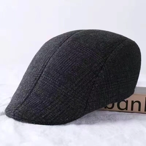 Detail shot of the thick dark grey wool-blend newsboy cap with textured tweed fabric