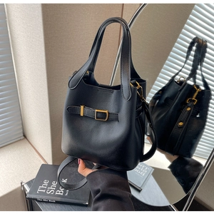 Detail of a black pebbled leather bucket bag with gold hardware and versatile straps