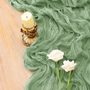 Elegant green wrinkled cheesecloth table runner with vintage gold candle holder and white roses