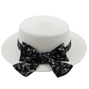 Detail of white boater hat featuring floral print black ribbon and oversized bow