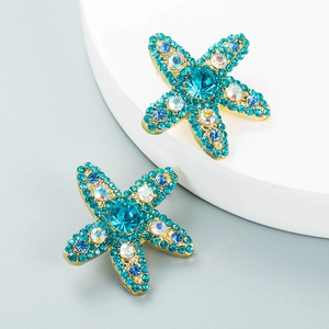 Macro detail of gold-plated starfish earrings with blue crystals and pearls