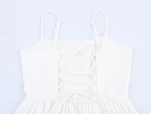 Detailed back view of white sundress featuring adjustable lace-up ties and ruched fabric
