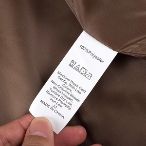 Detail of the washing label on a brown wool coat showing 100 percent polyester fabric care