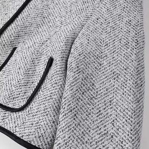 Close-up of high-quality black and white tweed jacket with premium leather trim details