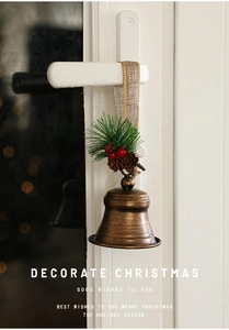 Retro Christmas metal bells with pine needles and berries hanging on a white door handle