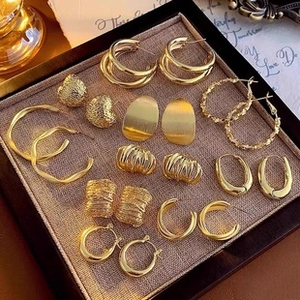 Detailed arrangement of gold earring set with hoops and geometric textures on jewelry tray
