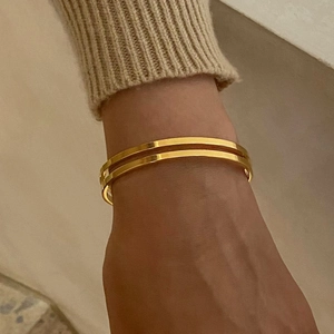 Detail of double-layer gold plated stainless steel open bangle on a wrist