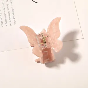 Detail of peach butterfly hair claw with marble texture and golden spring mechanism