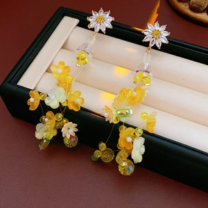Détail de boucles d'oreilles fleurs jaunes avec cristaux de zircon dans une boîte à bijoux