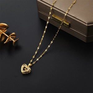 Elegant gold heart pendant necklace with shimmering crystals on a sleek black background