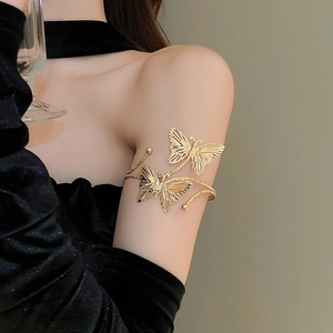 Close-up of a golden butterfly-shaped arm cuff on a model arm with elegant details