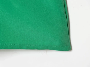 Detailed macro view of the vibrant green fabric texture and clean single-needle stitching