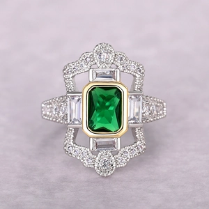 Anillo de lujo con gema verde corte esmeralda y halo de circonita dorada