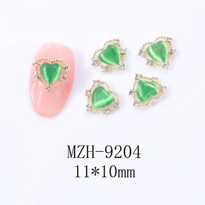 Détail du bijou d'ongle cœur œil-de-chat vert avec cadre doré et strass en cristal