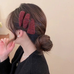 Detail of three burgundy tweed drop-shaped BB hair clips on female model's hair