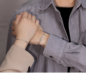 Close-up of couple holding hands wearing silver branch and tag bracelets on wrists