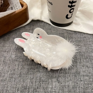 Detail of white marble hair claw clip with cute puppy shape and soft pom pom decoration