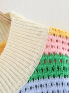 Gros plan d'un pull en maille rayé arc-en-ciel avec texture ajourée et col rond côtelé