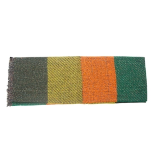 Detail of multi-color plaid knit scarf with fringes in green and orange tones