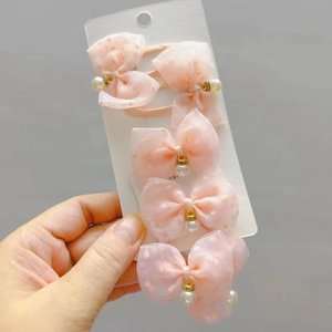Pink polka dot mesh bow hair clips with pearls on card holder detail view