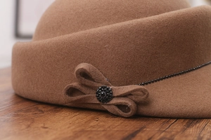 Detail of wool fedora hat featuring a bow and delicate black bead chain decoration