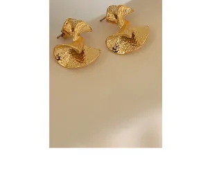 Macro shot of gold-plated stainless steel earrings with textured fan-shaped hammer pattern