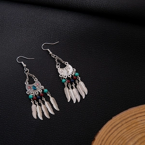 Detail view of Bohemian silver earrings with turquoise beads and metal feather pendants