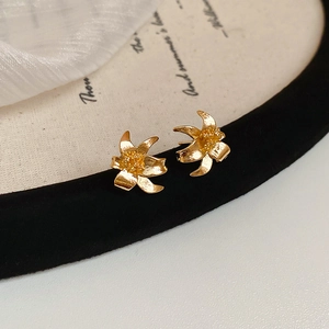 Macro view of gold lily petal earrings with textured stamens on an elegant display