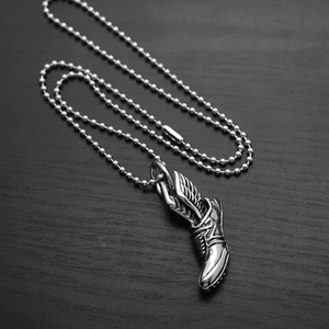 Vue détaillée du pendentif basket ailée en argent sur un fond en bois sombre