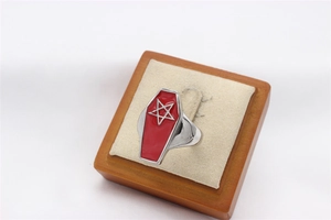 Close-up of gothic stainless steel coffin ring with red enamel and pentagram star