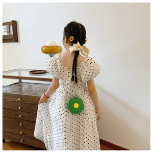 Rear view of a child wearing a green flower-shaped crossbody bag with a gold chain strap