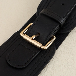 Close-up of a wide black elastic belt featuring a textured strap and a gold metal buckle