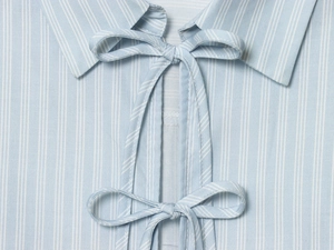 Détail de l'encolure d'une chemise en popeline rayée bleu clair avec double nœud papillon