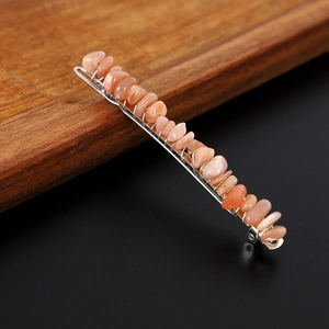 Dettaglio di un fermaglio per capelli con cristalli rosa avvolti su base metallica