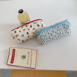 Detail of aesthetic quilted pencil cases with floral and checkered patterns shown with props