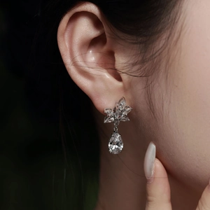 Macro shot of a 925 sterling silver drop earring with pear-cut zircon and flower stud