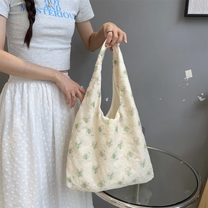 Detail of floral embroidery on cream canvas tote bag with wide shoulder strap