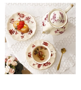 Service à thé vintage avec motif de roses rouges et bord doré sur nappe en dentelle