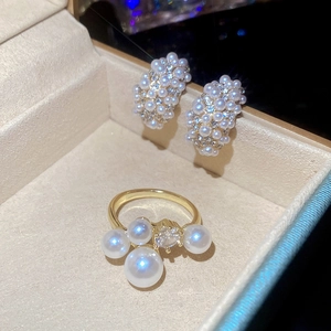 Close-up of pearl and rhinestone C-shaped earrings and ring set in a velvet box