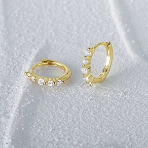 Macro detail of gold-plated S925 sterling silver huggie earrings with five inset zircons