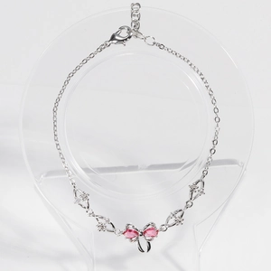 Elegant silver bow bracelet featuring pink teardrop zircons and white crystals on white backdrop