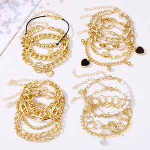 Detail of gold multilayer bracelet set with heart and star charms and T-bar clasp