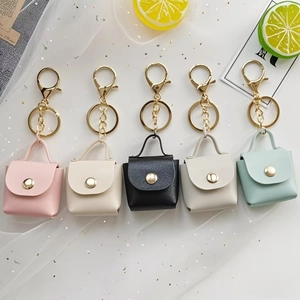 Close-up of mini leather keychain bags in five pastel colors with gold hardware
