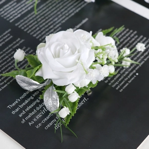 Elegant white silk rose boutonniere with green leaves and berries on black magazine