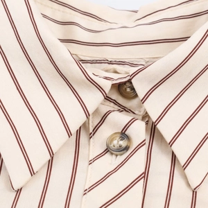Detalle macro de camisa a rayas con cuello de solapa y botones redondos de ámbar