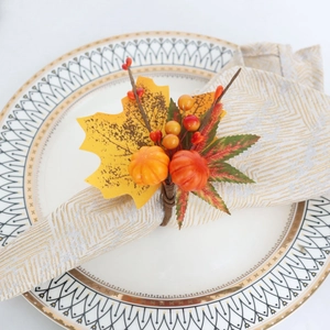 Détail d'un rond de serviette avec citrouilles et feuilles d'érable sur une assiette blanche